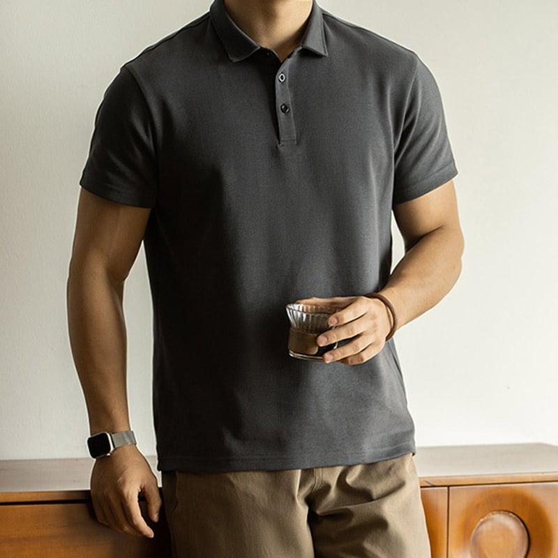 Lifestyle studio shot of menโs dark grey premium piquรฉ cotton polo shirt, traditional 2-button placket, structured rib collar and cuffs, breathable textured piquรฉ weave, relaxed tailored fit for everyday smart casual wear.