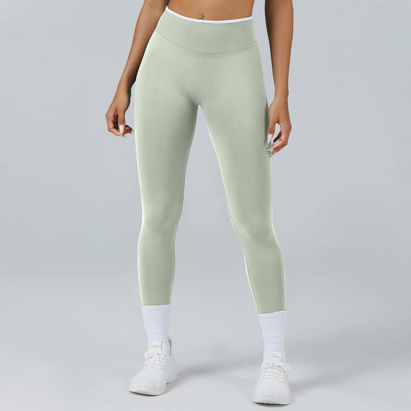 Full-body studio shot of womenโs pale sage seamless leggings constructed with 90 nylon 10 elastane stretch fabric, wide ribbed compression high waistband, full-length body-hugging fit, ultra-stretchy soft matte knit, moisture-wicking breathable material ideal for yoga, gym training and casual athleisure, OEM custom 90/10 nylon elastane legging supplier.