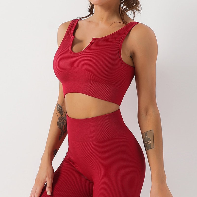 Front-side studio shot of womenโs burgundy full vertical ribbed seamless workout set, notch scoop neck sleeveless ribbed crop sports bra top, matching high rib compression waist full-length leggings, stretch nylon spandex rib knit, breathable squat-proof fabric for yoga, gym training and casual athleisure, OEM ribbed crop top legging set wholesale supplier.