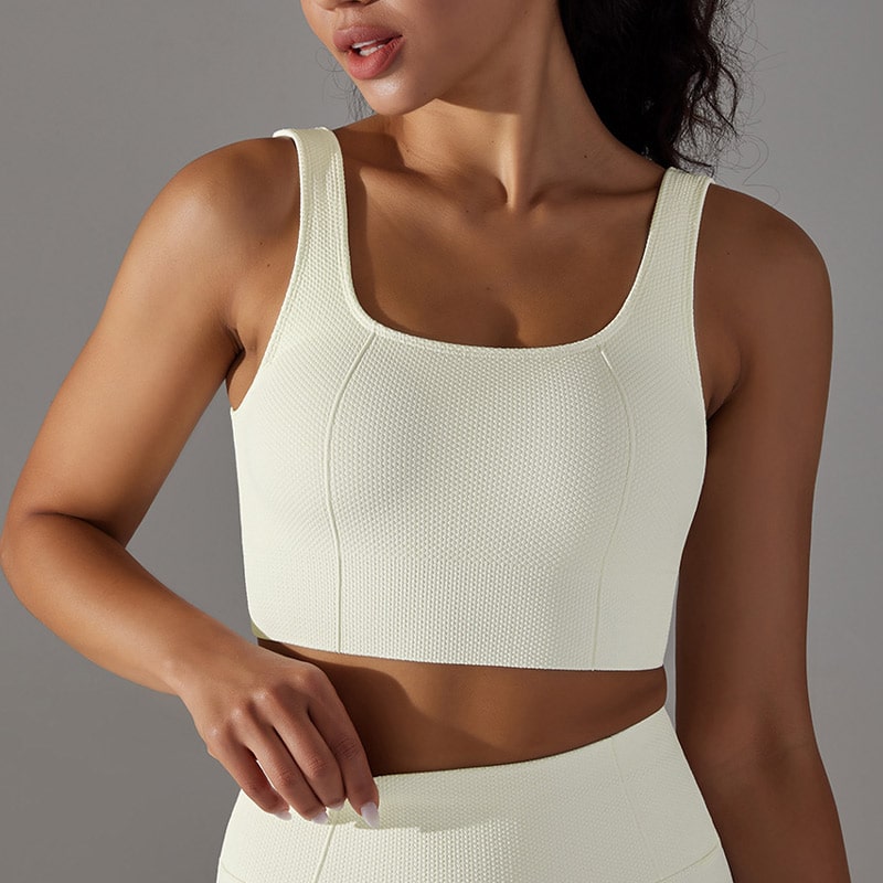 Front close-up studio shot of womenโs cream high-compression gym crop top, wide square neckline, thick supportive shoulder straps, bust darts, textured waffle knit seamless fabric, medium-high compression fit, ribbed underbust band for gym, training, running and yoga, OEM high-compression gym crop top manufacturer.
