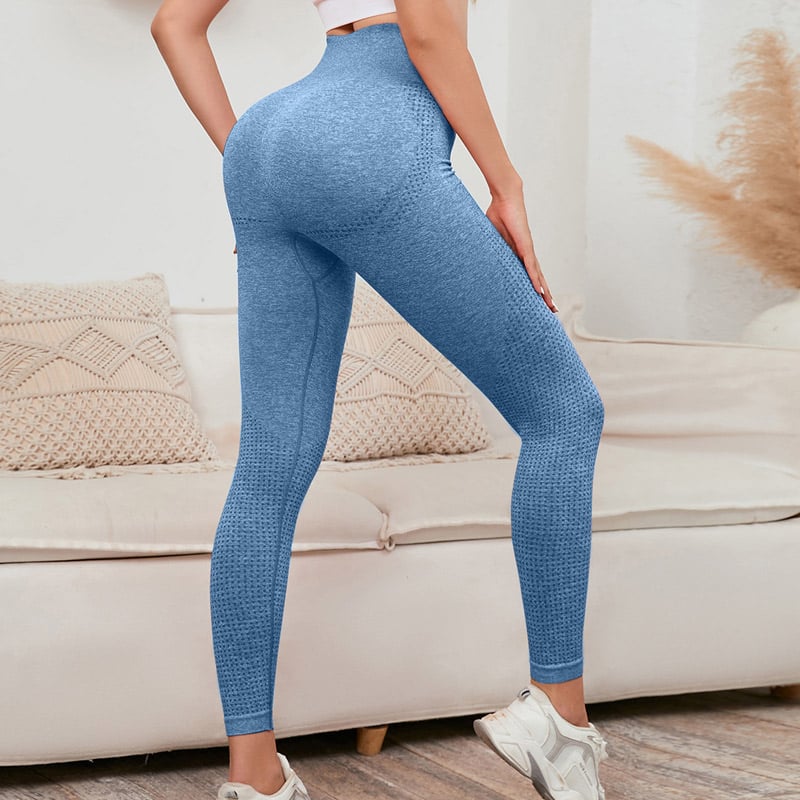 Rear angle lifestyle studio shot of womenโs blue heather seamless leggings made from custom nylon polyester spandex blend, hexagonal rib texture, contour scrunch butt lifting design, high compression waistband, full-length sculpting fit, breathable stretch knit for yoga, gym and casual athleisure, OEM custom nylon polyester spandex legging manufacturer.