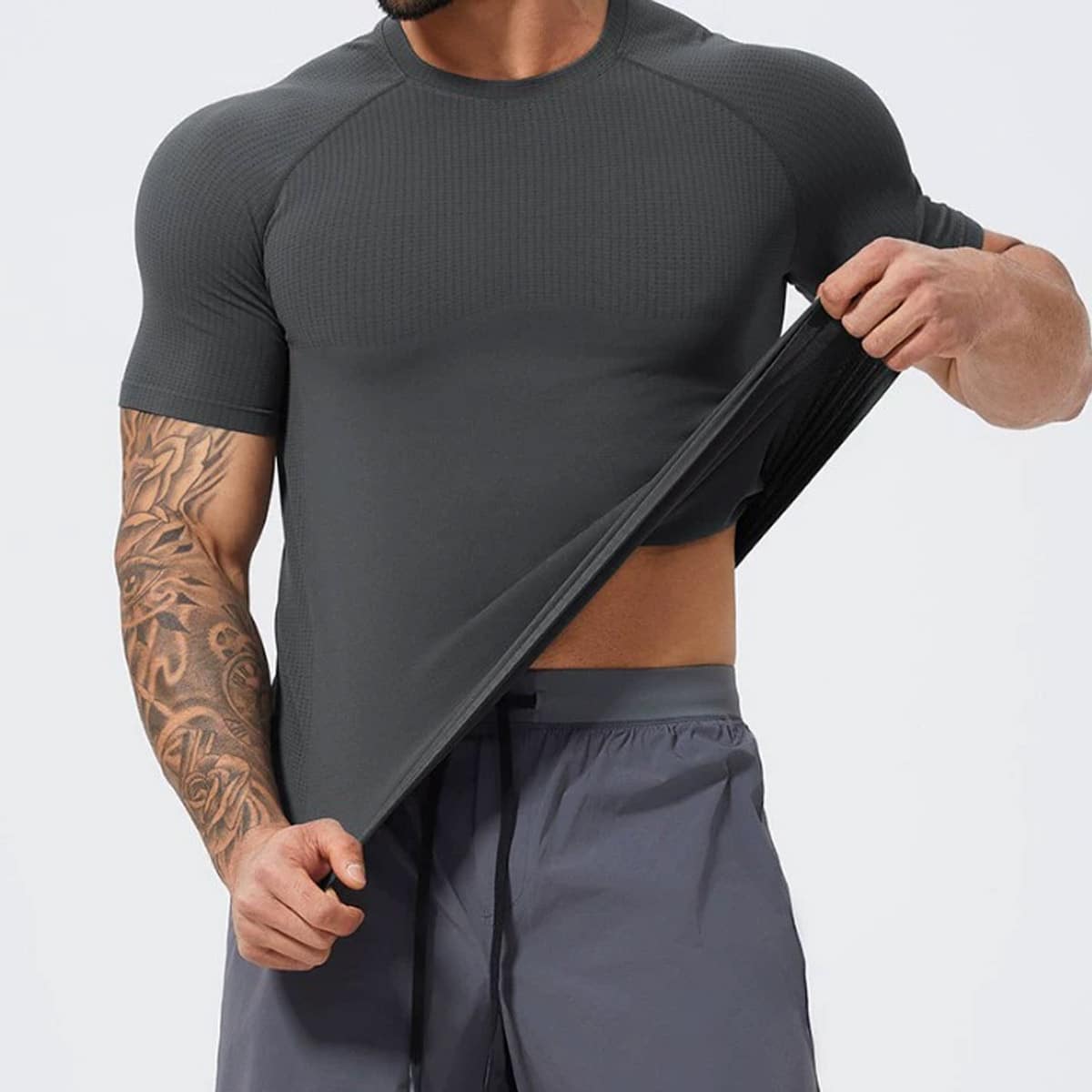 Studio shot of menโs dark grey seamless raglan short sleeve tee, crew neck design, waffle jacquard breathable mesh panels on chest & shoulders, ultra-stretchy seamless performance knit fabric, compression athletic fit, moisture-wick quick-dry material for weightlifting, running and daily training, direct mens seamless t-shirt factory bulk wholesale supply.