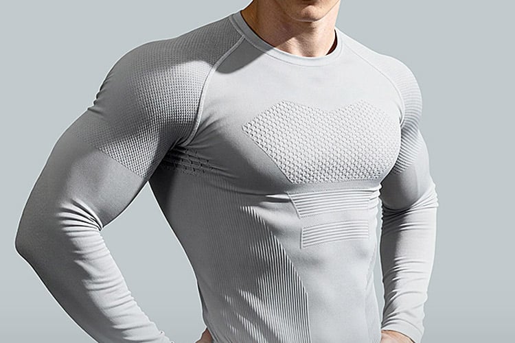 Half-body studio shot of menโs light gray antimicrobial seamless compression long sleeve shirt, raglan construction with segmented engineered mesh ventilation panels on chest, shoulder and torso, ribbed stretch contour zones, spun-in silver antibacterial odor-control fabric, body-sculpting fit for gym, running and outdoor sports, OEM technical antimicrobial activewear compression top supplier.