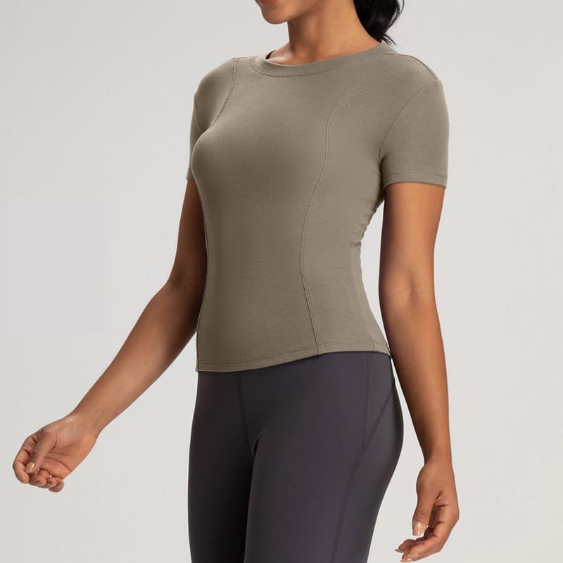 Studio shot of womenโs taupe merino wool seamless short sleeve base layer tee, crew neck contour seamed raglan silhouette, slim cropped fitted cut, natural temperature-regulating merino blend fabric, odor-resistant breathable seamless performance top for yoga, hiking and daily layering, OEM merino seamless base layer supplier.